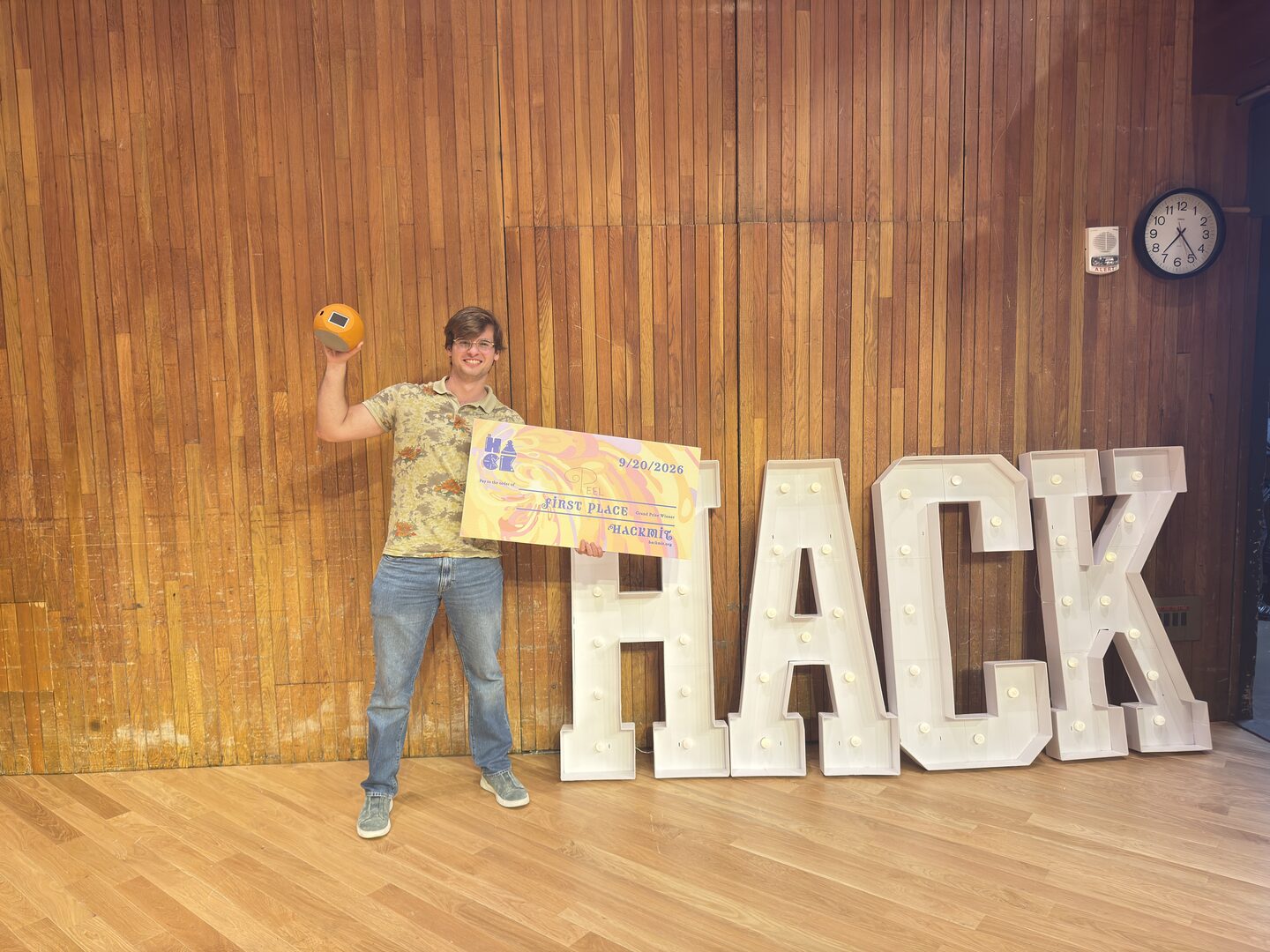 Viktor on stage holding the Peel device and HackMIT first-place award